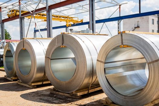 Stainless steel rolls. Rolls of steel sheet in the warehouse. A roll of galvanized steel sheet for the production of metal pipes and tubes in a factory