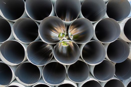 Downpipe warehouse. Steel pipes, parts for the construction of a roof drainage system in a warehouse. Stack of stainless steel pipes