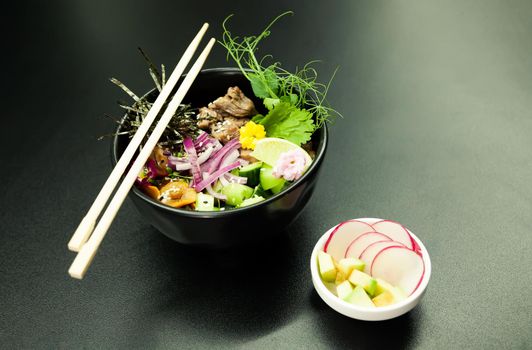 Poke salad with beef in a bowl. Ingredients Beef, Nameko mushrooms, cherry tomatoes, rice, cucumber, red onion, Kim Chi sauce, Ponzu sauce, nori, sesame seeds, cilantro, lime. Asian salad concept.