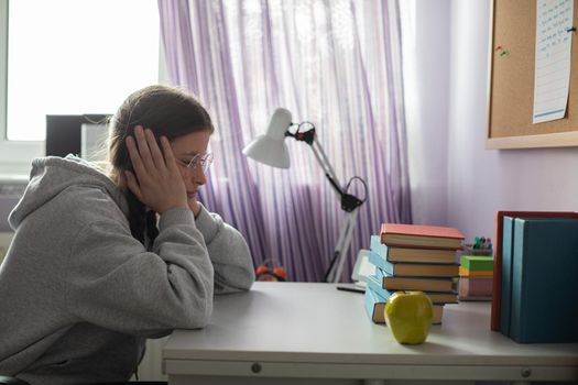 A girl sits at her desk and wonders how she will read all those school readings during the school year. A young girl with pigtails.