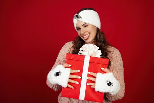 Happy woman holding a gift box. Portrait of happy smiling girl looking at delivered wrapped box isolated on red background