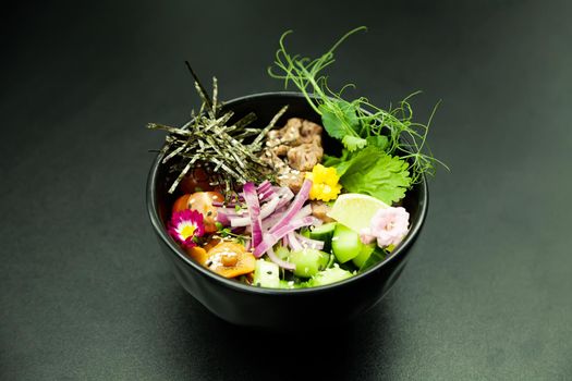 Poke salad with beef in a bowl. Ingredients Beef, Nameko mushrooms, cherry tomatoes, rice, cucumber, red onion, Kim Chi sauce, Ponzu sauce, nori, sesame seeds, cilantro, lime. Asian salad concept.