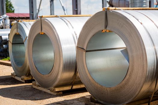 Stainless steel rolls. Rolls of steel sheet in the warehouse. A roll of galvanized steel sheet for the production of metal pipes and tubes in a factory