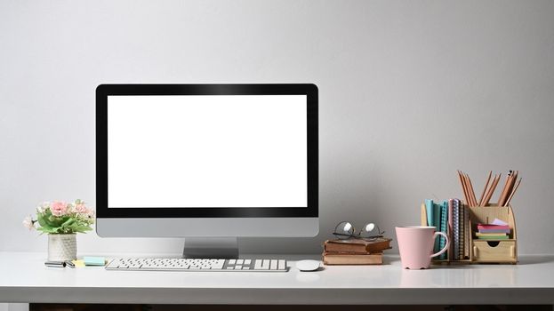 Front view mock up computer, coffee cup, flower pot and stationery on white table. Empty screen for advertise text.