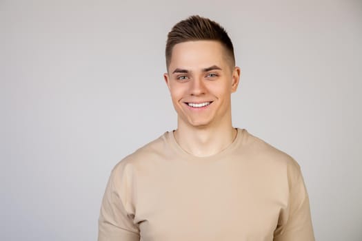 Handsome young man with stylish hairstyle looking at the camera with a smile on his face. Photo of young attractive handsome modern freelancer, entrepreneur, student looking at camera.