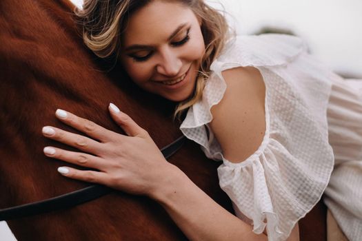 A woman in a white sundress riding a horse near a farm.