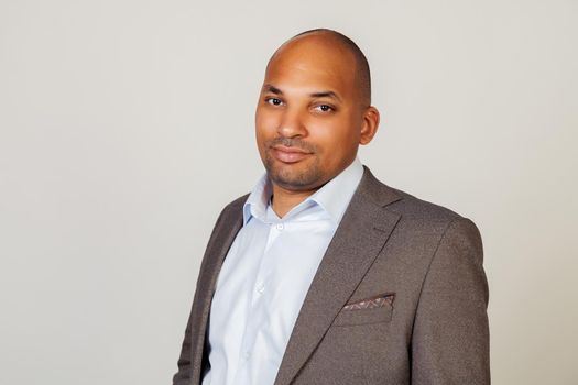African American man looking into the camera with a serious expression. Business man businessman in classic suit looking at camera while standing on gray background