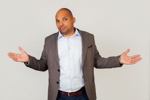 Disgruntled tense and worried young male African American businessman with a cynical and angry expression spread his hands in a helpless gesture spreading his palms, as if he didn t know what to do..