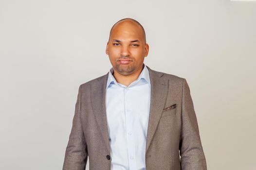 African American man looking into the camera with a serious expression. Business man businessman in classic suit looking at camera while standing on gray background