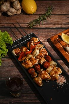 Grilled vegetable and chicken skewers with spices, herbs and vegetables on wooden background.