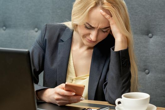 Worried young woman looking surprised while using the smartphone at cafe.