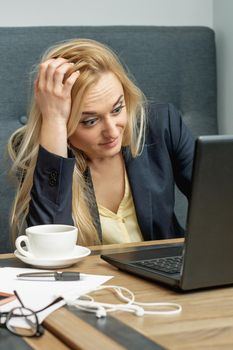 Frustrated young woman looking surprised working on laptop at home office.