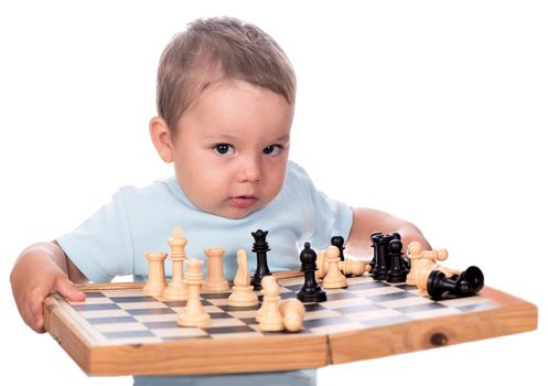 little boy staring at the chess pieces