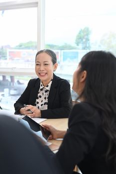 Attentive middle aged female team leader listening intently during discussion of business ideas in modern office.