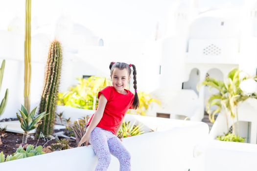 beautiful little girl stands among a small green leaf beautiful plants in spring and summer on a sunny day