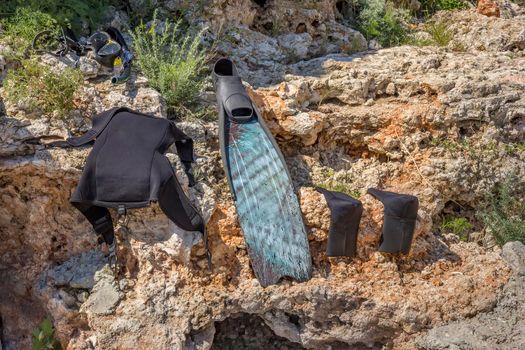 Wet parts of diving equipment drying out in the sun on the rocks