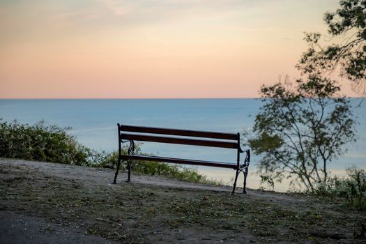 Wooden bench with a view at sea and day sky. Beautiful place for relaxing and enjoying nature. Traveling stop for travelers. 