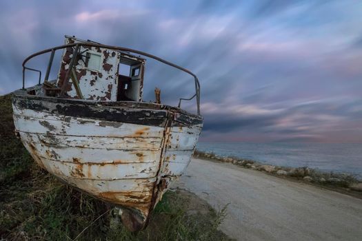 An abandoned old wooden fishing boat on the beach with amazing sky