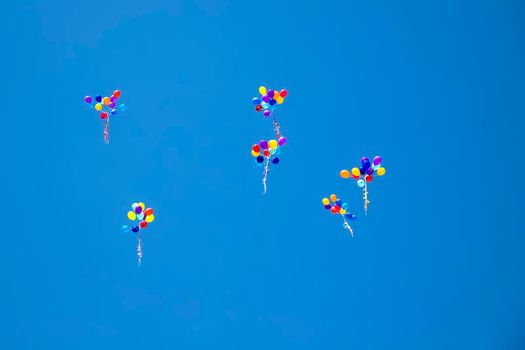 The multi colored helium balloons flying In the blue sky. the concept of a wedding, celebration, anniversary, entertainment