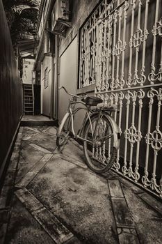 Old bicycle in black and white. Bike left at the fence on the street