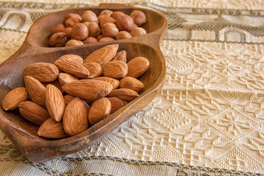 Almonds and hazelnuts in the wooden bowl on the table, close-up