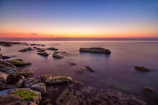 Relaxing long exposure seascape of rocky coast before sunrise.