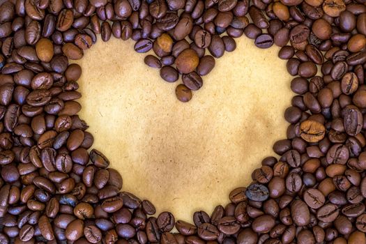 Morning heart. Heart shape made from coffee beans at a vintage paper background