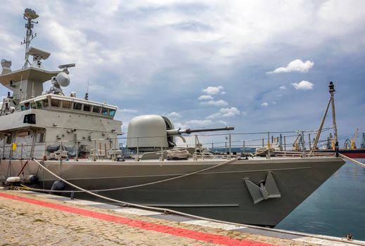 A part of a military warship in port. Military sea landscape with cloudy sky.
