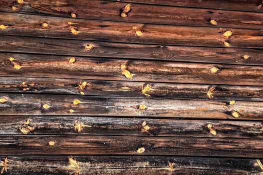 The wall of a building or house of old cracked logs. The surface with wooden boards. Old village barn or warehouse.