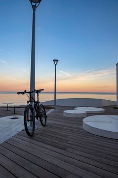 Idyllic scene of a bicycle standing near the sea propped on a pillar with blue sky as background