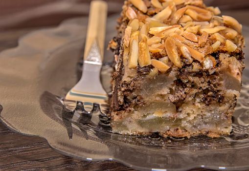 Close view of a delicate piece of chocolate cake, torte with nuts on a plate with a fork. 