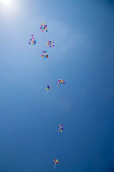 The multi colored helium balloons flying In the blue sky. the concept of a wedding, celebration, anniversary, entertainment