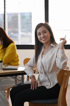 Attentive young woman listening intently to her colleague during discussion of business ideas in modern office.