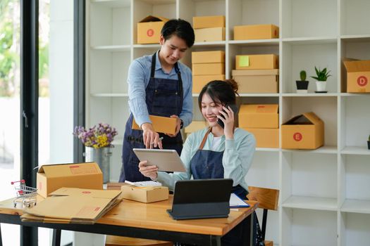 Asian couples doing SMEs deliver their products online to customers who order products via the Internet, helping to sell happily : Work From Home online.