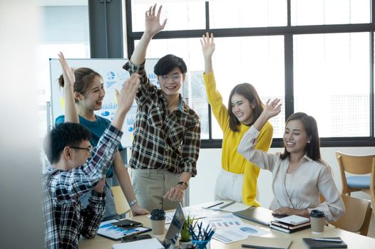 Succesful business team celebrating corporate victory together in office.