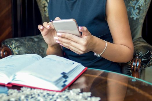 Business woman is using smartphone working from home sitting on armchair looking at camera. Stay home and quarantine concept.