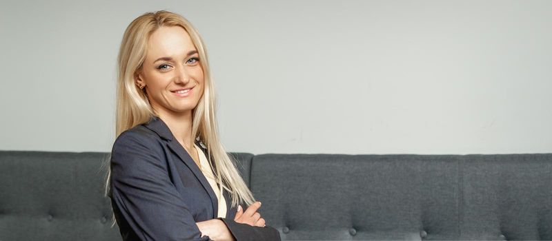 Beautiful caucasian business woman smiling at the camera with folded arms in office.