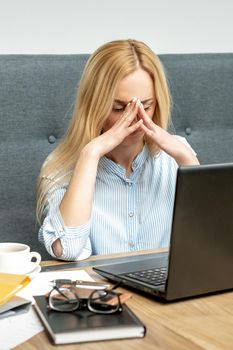 Tired young business woman sitting in front of laptop at office.