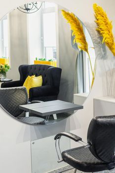 Interior of modern beauty and hairdresser salon with armchair and mirror in yellow and black tones.