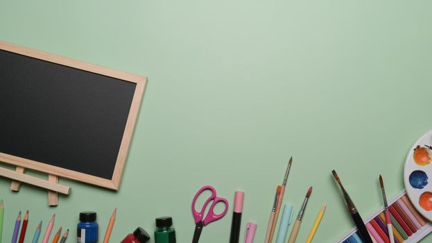 Top view empty chalkboard and school stationery on green background. Back to school concept.