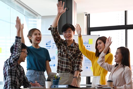 Excited business team celebrating corporate victory together in office.