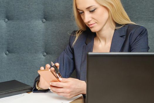 Beautiful young business woman using smartphone at the table in home office.