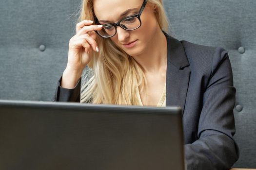 Busy business woman wearing eyeglasses working on laptop at home office.