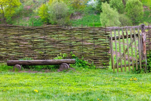 horizontal wattle fence with wicket and wooden bench near at summer day in Yasnaya Polyana, Russia