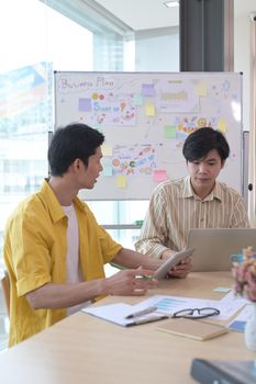 Two young businessman are discussing ideas of new startup project together at modern office.