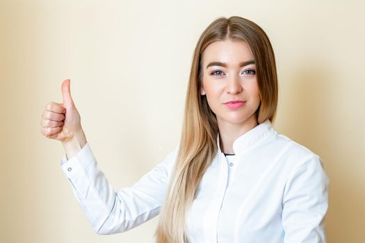 Beautiful young woman is showing thumbs up wearing white shirt over yellow background looking at camera.