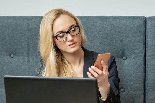 Young woman is using smartphone sitting at wooden table in coffee shop.