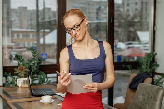 Portrait of young business woman holding and reading the documents in office.