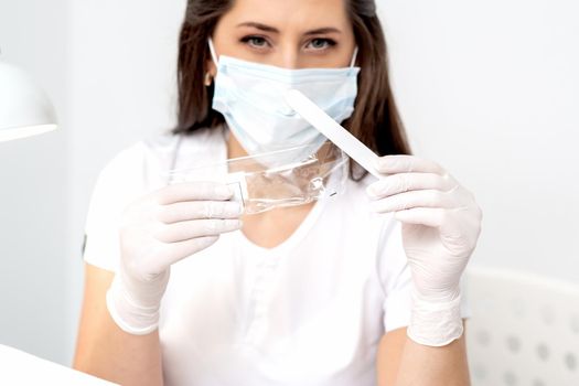 Woman holding medical tool wearing mask in salon.