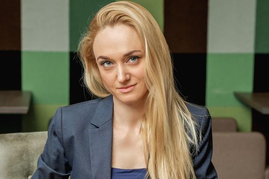 Portrait of beautiful young business woman holding office supplies sitting in office.